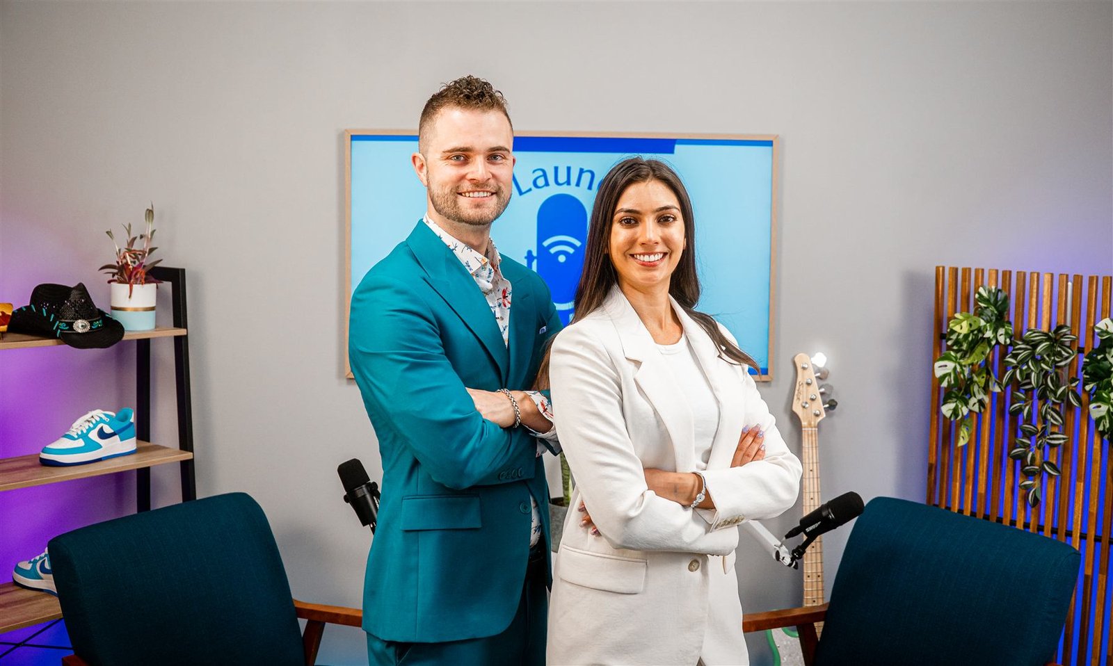Two clients standing confidently in front of the branded Social Launch Labs backdrop, ready to record